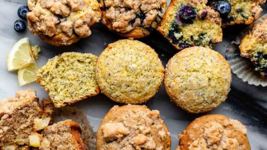 different flavors of muffins lined up on marble backdrop.