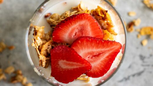 Sliced strawberries, granola and milk in a glass.