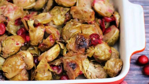 Roasted Brussels sprouts with cranberries in a red serving dish.