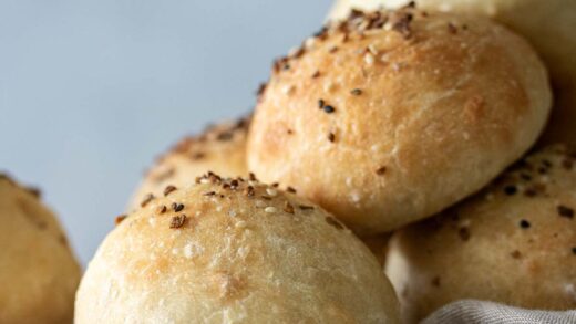 Baked focaccia rolls on top of wooden board.