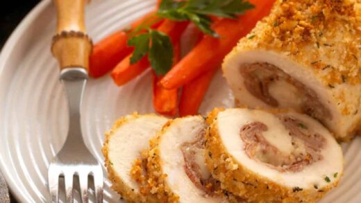 Chicken Cordon Bleu on a white plate with carrots and a fork.