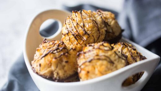 Bowl full of coconut macaroons with dark chocolate drizzle.