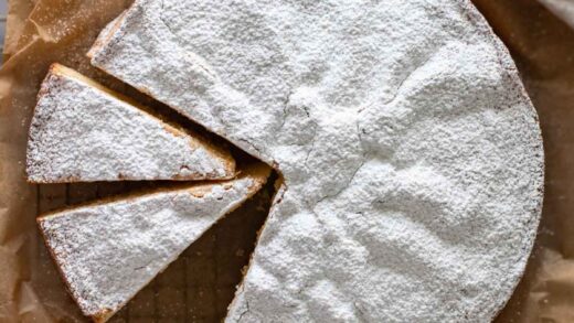 A Torta Paradiso, sliced, over parchment paper, with icing sugar.