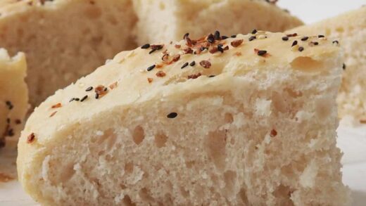 Slice of Focaccia on a white bench. In the background are more slices of Focaccia.