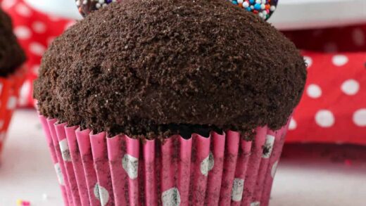 Close up of a Minnie Mouse cupcake topped with a pink candy bow.