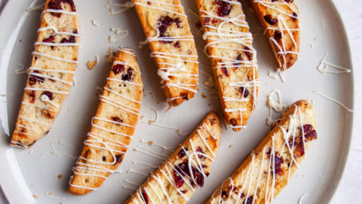 All the biscotti laid out on a white plate drizzled with white chocolate