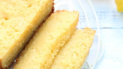 Sliced cake on rack with lemons behind.