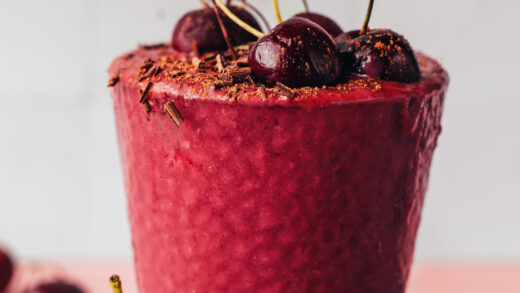 Placing a cherry on top of a glass filled with our chocolate cherry protein shake recipe