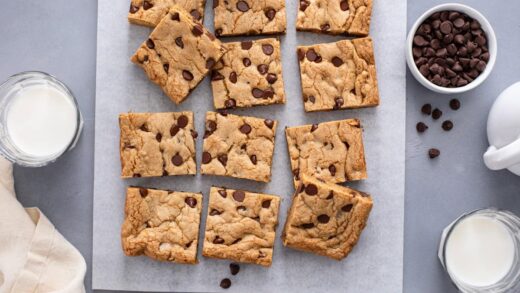 Overhead view of sliced chocolate chip cookie bars on a piece of parchment paper.