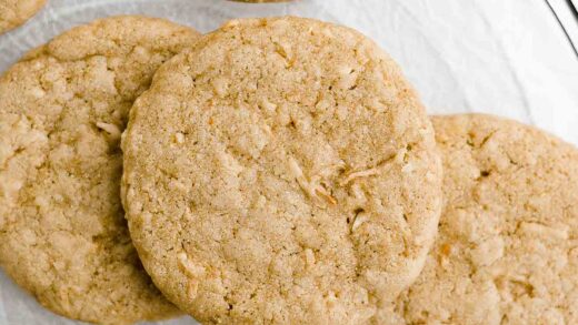 overhead view of healthy coconut cookies arranged on a circular wire cooling rack – easy recipe – chewy, soft, vegan, eggless, dairy free, low fat, low calorie, and clean eating with whole wheat and gluten free options – made with coconut oil, shredded coconut, and coconut extract with no refined sugar