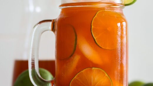 Thai Tea lemonade in a mug with lime slices and ice.