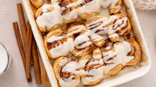 Overhead view of puff pastry cinnamon rolls in a white baking pan.