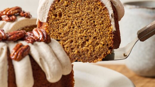 Slice of pumpkin bundt cake being lifted up from plate with cake server.